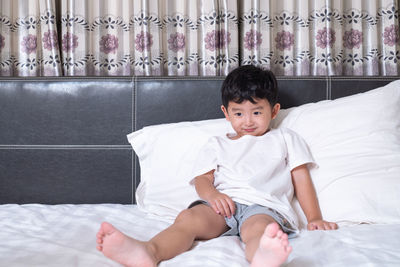 Boy sitting on bed at home