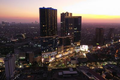 High angle view of illuminated city buildings against sky during sunset