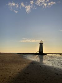 Lighthouse by sea against sky