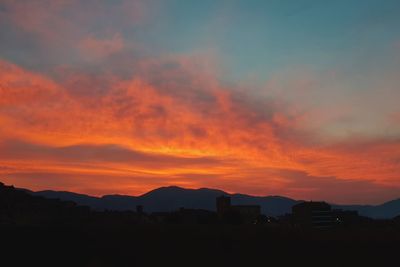 Silhouette landscape against dramatic sky during sunset