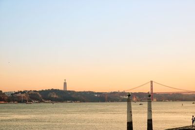 Suspension bridge over river against sky during sunset