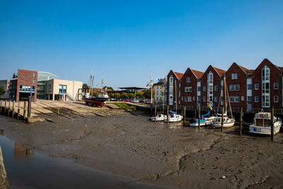 Houses by buildings against clear blue sky