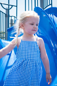 Close-up of girl looking away while standing against slide at playground