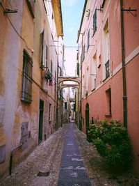 Walkway amidst buildings against sky