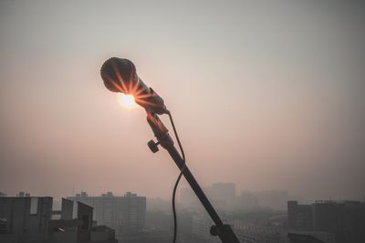 Silhouette man holding cityscape against sky during sunset