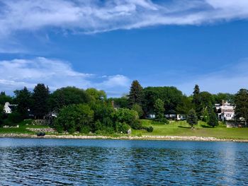 Scenic view of lake by trees and building against sky