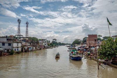 Sailboats moored on river by buildings in city against sky
