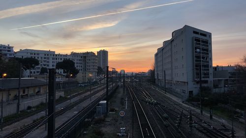 High angle view of railroad tracks amidst buildings against sky during sunset