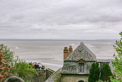 People on building by sea against sky