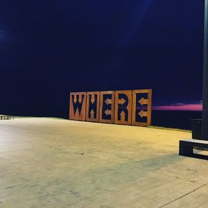 Information sign on beach against sky at night