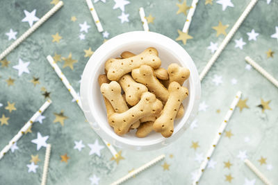 Dog treats, bone biscuits in white bowl on festive birthday green background.