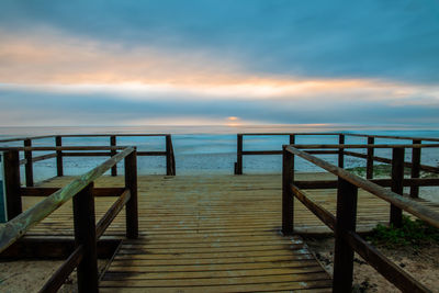 Wooden pier on sea against sky during sunset