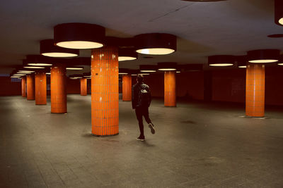Full length and rear view of man walking in illuminated corridor