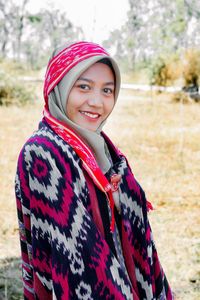 Portrait of smiling young woman standing on field