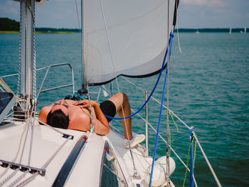 Young person sunbathing on a sailboat under the sail person