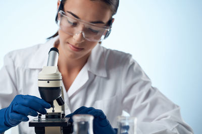 Doctor holding medicine while standing against white background