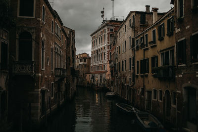 Canal amidst buildings in city against sky