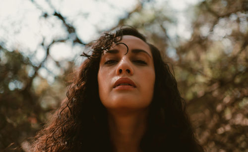 Portrait of young woman against trees