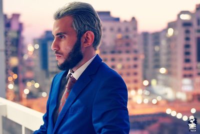 Young businessman standing against illuminated city