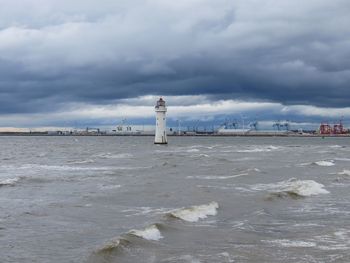 Lighthouse by sea against sky