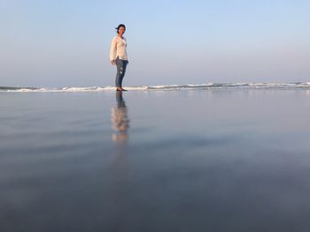 Portrait of woman standing at beach against clear sky