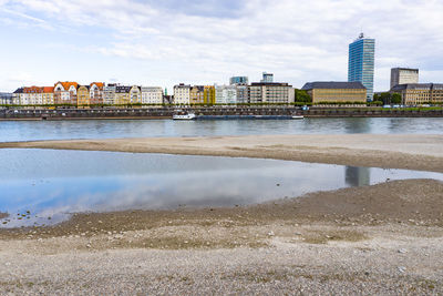 Scenic view of river by buildings against sky