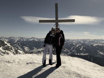 Rear view of man standing on snowcapped mountain against sky