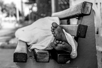 Low section of homeless man sleeping on bench