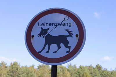 Close-up of road sign against blue sky