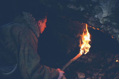 Boy holding flaming torch in cave