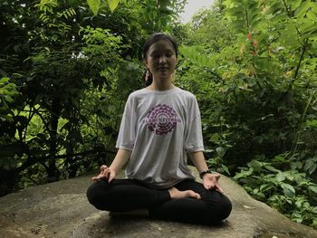 Full length of teenage girl sitting on plant