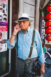 Man wearing hat standing against built structure