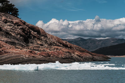 Scenic view of sea by mountains against sky