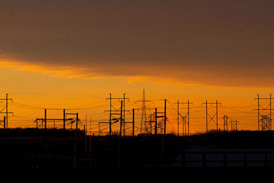 Silhouette electricity pylons against romantic sky at sunset