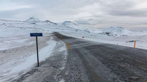 Full frame view of snow blowing across a mountain pass road with a road sign