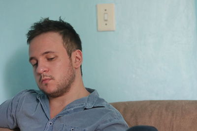 Portrait of young man against wall at home