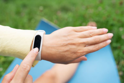 The girl does stretching and looks at the fitness bracelet and checks her breathing during exercise.