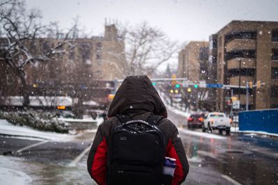 Rear view of man on snow against sky in city