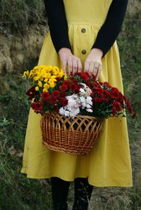 Midsection of woman holding yellow flower