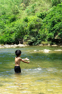 Rear view of shirtless man in water