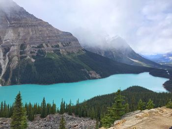 Scenic view of calm lake against mountains during foggy weather