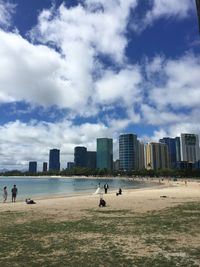 People on beach against buildings in city