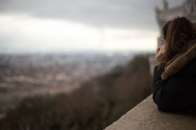 Rear view of woman sitting on landscape against sky