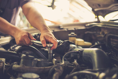 Midsection of male mechanic repairing car in shop