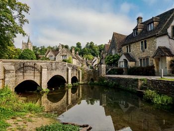 Arch bridge over river by building against sky