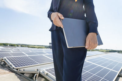 Hands of businesswoman holding laptop in front of solar panels