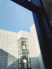 Low angle view of glass building against clear blue sky