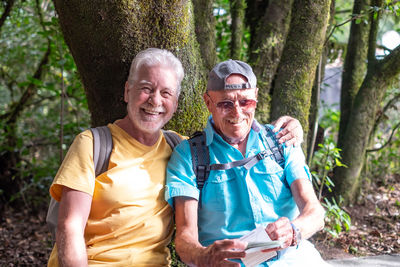 Portrait of smiling friends standing in forest