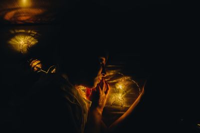 Portrait of woman with illuminated lights in dark room