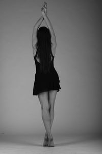 Rear view of woman dancing against gray background